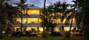 a lit up building with palm trees in front of it at Balboa Apartments in Port Douglas