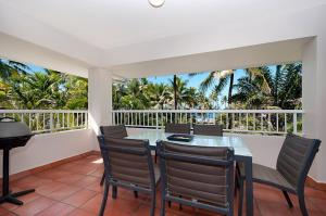 a dining room with a table and chairs and a balcony at Balboa Apartments in Port Douglas