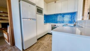  La cuisine est équipée de placards blancs et d'un réfrigérateur. dans l'établissement By The Sea Unit 4 13 Esplanade Kings Beach, à Caloundra