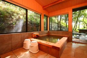 jacuzzi en una habitación con grandes ventanas en Kurasako Onsen Sakura en Minamioguni