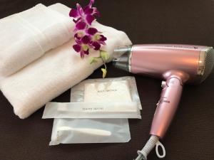 a pink hairdryer next to a towel and a flower at Resort Villa The ReLa Inn in Onna