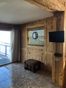a living room with wooden walls and a flat screen tv at Capri Beach Hotel in Corpus Christi