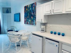 uma cozinha com armários brancos e uma mesa e cadeiras em SOBE OCEAN VIEW OCEAN DR charming studio -316 em Miami Beach
