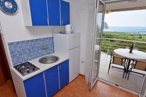 cocina con armarios azules y fregadero y balcón en Apartments Siljak, en Petrovac na Moru