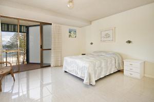 a white bedroom with a bed and a balcony at Lowanna Unit 10 24 Bulcock Beach Esplanade Bulcock Beach in Caloundra