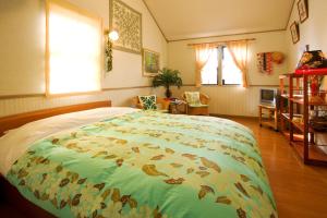 ペンションカパルア軽井沢 في كارويزاوا: غرفة نوم مع سرير كبير مع بطانية ملونة