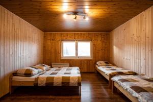 two beds in a room with wooden walls and a window at Wellness Chalet Harmonia in Hriňová