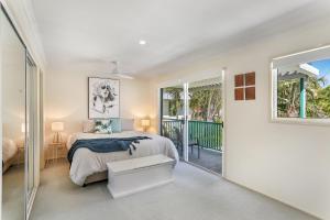 a bedroom with a bed and a balcony at Clouds End in Noosaville