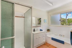 a bathroom with a shower and a tub and a sink at Clouds End in Noosaville