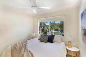 a bedroom with a white bed with a window at Clouds End in Noosaville