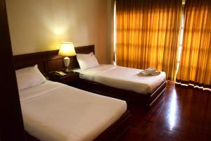 ein Hotelzimmer mit 2 Betten und einer Lampe in der Unterkunft Puangpen Villa Hotel in Hua Hin