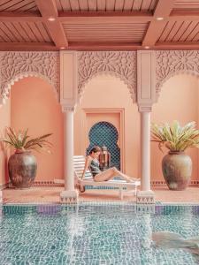 a woman sitting on a bench next to a swimming pool at Kenting Amanda Hotel in Nanwan