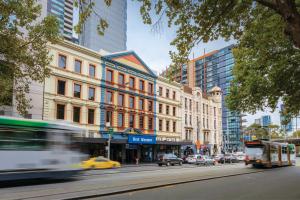 una concurrida calle de la ciudad con edificios y un autobús en Best Western Melbourne City, en Melbourne