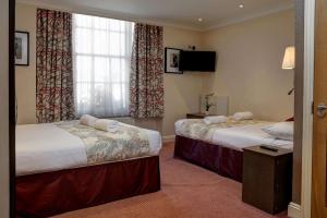 a hotel room with two beds and a television at Best Western Buckingham Palace Rd in London