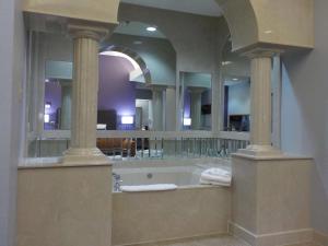 a bathroom with a tub with a large mirror at SureStay Plus Hotel by Best Western Warner Robins AFB in Warner Robins +32 photos