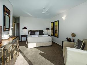 een slaapkamer met een bed en een bank bij A Little Cove treasure, Noosa Heads in Noosa Heads