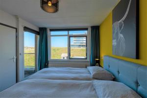 ein Schlafzimmer mit einem Bett und einem großen Fenster in der Unterkunft CasaMare in Egmond aan Zee