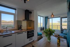 eine Küche mit einem Tisch und ein Wohnzimmer mit einem Sofa in der Unterkunft CasaMare in Egmond aan Zee