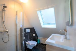 ein Badezimmer mit Toilette und Waschbecken und einem Fenster in der Unterkunft CasaMare in Egmond aan Zee + 63 Fotos