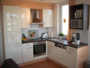 una cucina con mobili bianchi e un forno a piano cottura di Windrose 7 a Grossenbrode Altre 23 foto