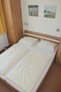 two beds with white sheets on them in a room at Ferienwohnung Windrose 7 in Großenbrode