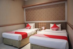 two beds in a hotel room with red pillows at Super OYO 742 Mona Plaza Hotel in Pekanbaru