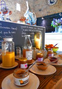 a table topped with plates of food and jars of honey at Yourtes de Vassivière in Peyrat-le-Château
