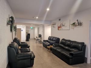 a waiting room with black leather couches and chairs at Quokka Backpackers Hostel Perth - note - Valid passport required to check in in Perth