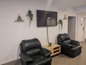 a living room with two leather chairs and a flat screen tv at Quokka Backpackers Hostel Perth - note - Valid passport required to check in in Perth