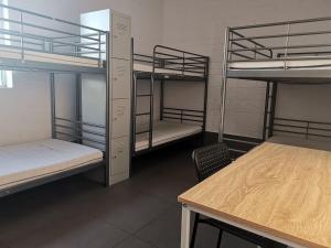 Habitación con 3 literas y mesa. en Quokka Backpackers Hostel Perth - note - Valid passport required to check in en Perth