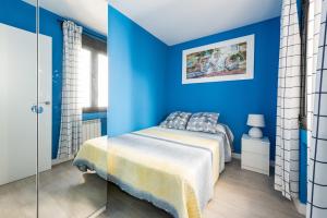 Dormitorio azul con cama y pared de cristal en Ever House - ALCALA BRISA Gran TERRAZA ROOFTOP en Madrid