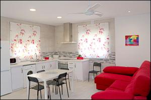 un soggiorno con un divano rosso e una cucina di Chalet Peñuelas con piscina a Conil de la Frontera