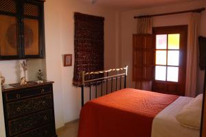 a bedroom with a bed and a dresser and a window at Casa Nieves in Ronda