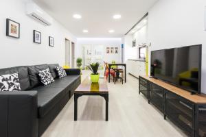 sala de estar con sofá negro y TV en Ever House - ALCALA BRISA Gran TERRAZA ROOFTOP en Madrid