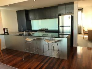 a kitchen with a counter with stools and a refrigerator at Beachside Apartments Bonbeach in Bonbeach