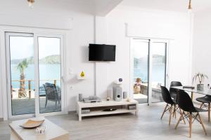 a white living room with a table and chairs at Iliana Sea Side House in Elounda