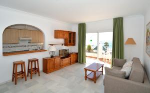 a living room with a couch and a kitchen at Apartamentos HC Burriana Playa in Nerja