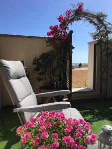 a chair and a table with flowers on a patio at Beach flat with garden in Castelldefels +15 photos