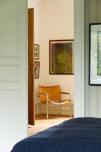 a bedroom with a chair and a painting on the wall at Liebacksgården in Skegrie