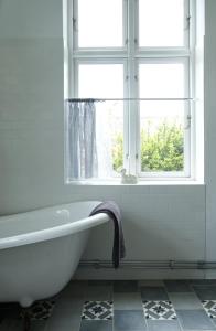 a white bath tub in a bathroom with a window at Liebacksgården in Skegrie