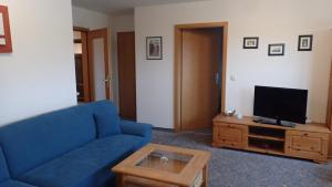 a living room with a blue couch and a tv at Gästehaus Siebert in Lobbe