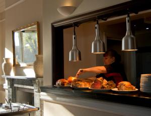 a woman behind a counter with plates of food at Crofts Hotel in Cardiff