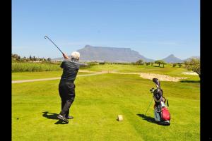 a man swinging a golf club on a golf course at Milnerton Guesthouse in Cape Town