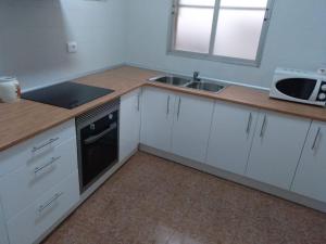 eine Küche mit weißen Schränken, einer Spüle und einer Mikrowelle in der Unterkunft Casa Vall de Almonacid in Vall de Almonacid
