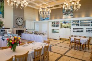 a restaurant with white tables and chairs and a clock at Georgalas Sun Beach Resort in Nea Kallikrateia
