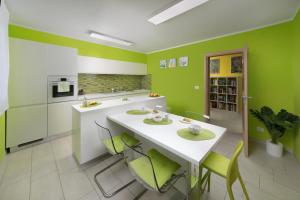 een keuken met groene muren en een witte tafel en stoelen bij RAINBOW in Pula