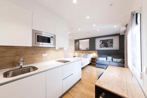 a kitchen with white cabinets and a living room at Antique Pamplona Tres Reyes Apartments in Pamplona