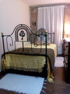 1 dormitorio con cama de metal negro y alfombra en A Casinha do Beco, en Gouveia