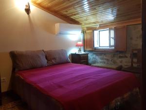 a bedroom with a large purple bed with a window at A Casinha do Beco in Gouveia
