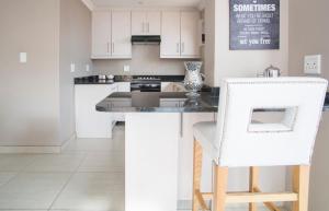 a kitchen with white cabinets and a white chair at Milnerton Guesthouse in Cape Town +16 photos